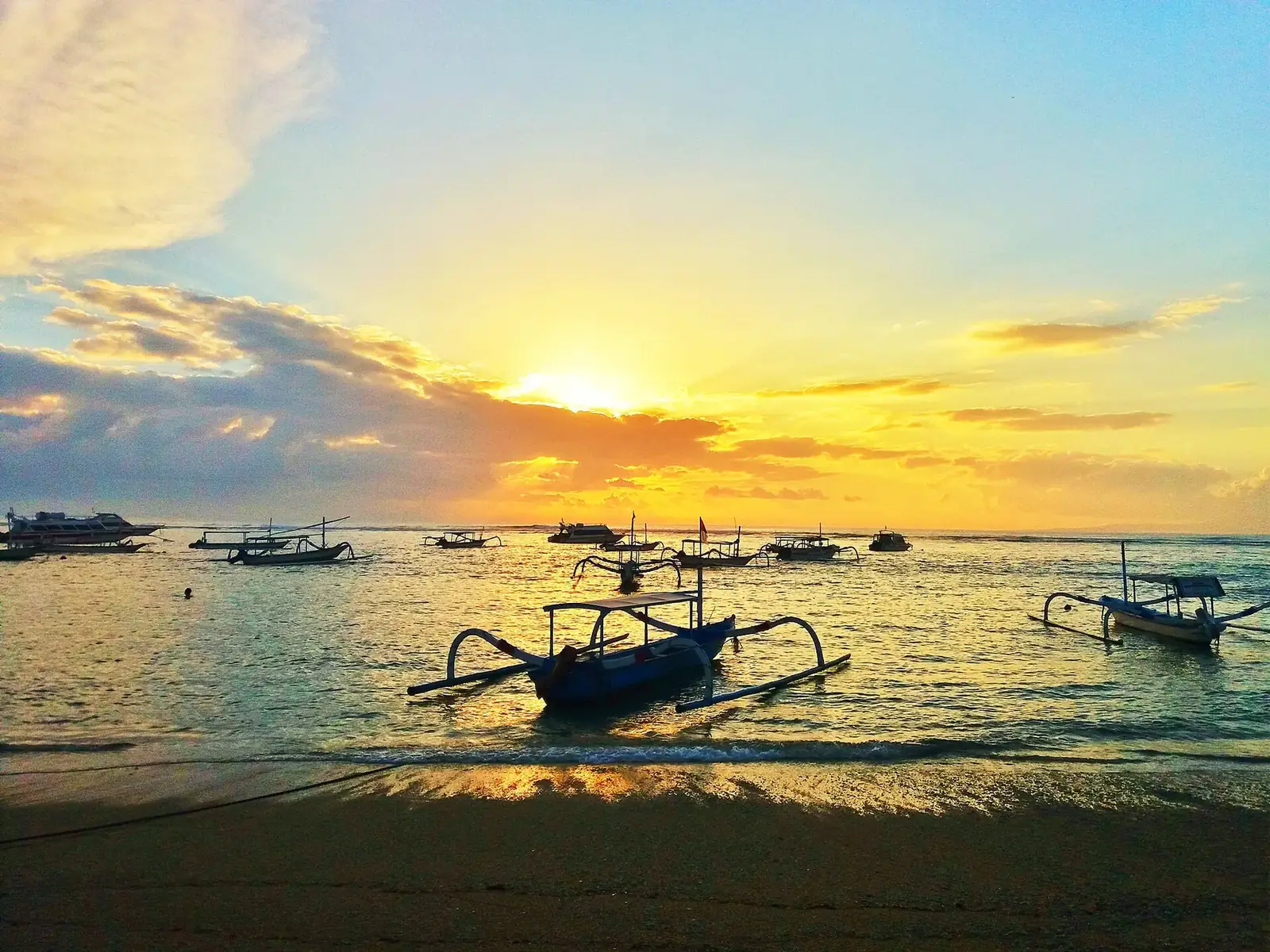 Traditional outrigger boats moored off Sanur at sunrise